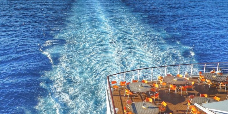 Photo of a cruise ship and the wake behind it in the sea.